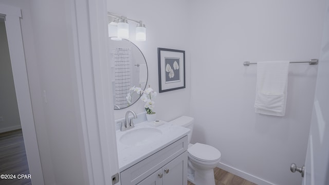 bathroom featuring wood-type flooring, vanity, and toilet