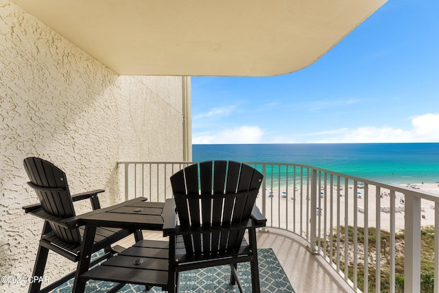 balcony with a water view and a view of the beach