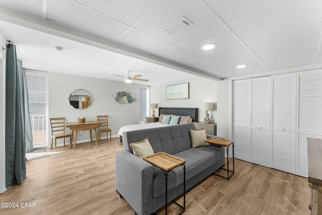 bedroom with ceiling fan, a closet, a paneled ceiling, and light hardwood / wood-style floors