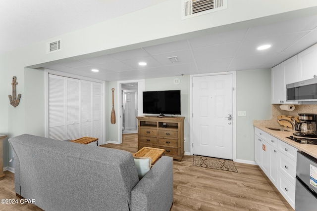 living room with a paneled ceiling, sink, and light hardwood / wood-style flooring