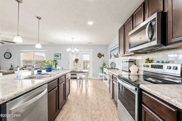 kitchen with hanging light fixtures, sink, dark brown cabinets, stainless steel appliances, and light wood-type flooring