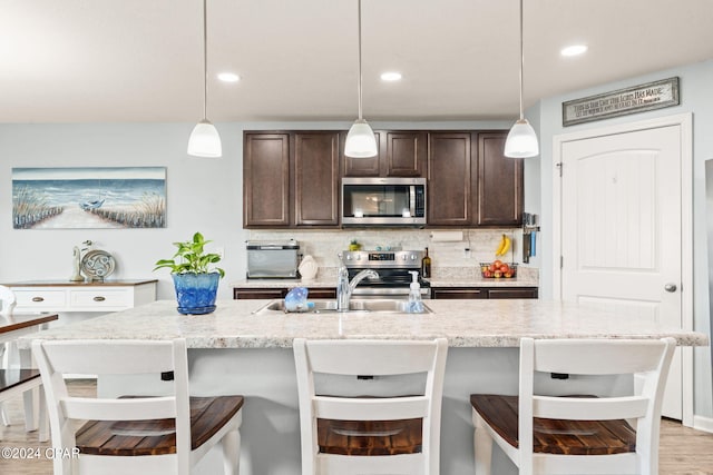 kitchen featuring hanging light fixtures, dark brown cabinetry, light hardwood / wood-style flooring, and stainless steel appliances