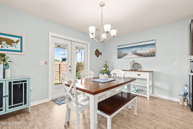 dining space with light hardwood / wood-style flooring, an inviting chandelier, and french doors