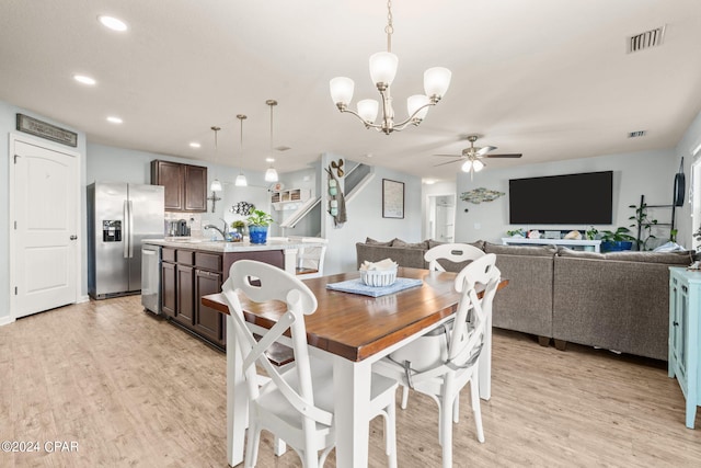 dining space featuring ceiling fan with notable chandelier, light hardwood / wood-style floors, and sink