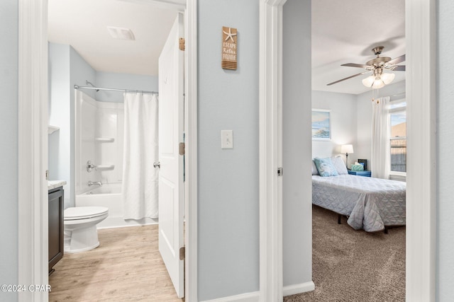 full bathroom with shower / bath combination with curtain, wood-type flooring, ceiling fan, vanity, and toilet