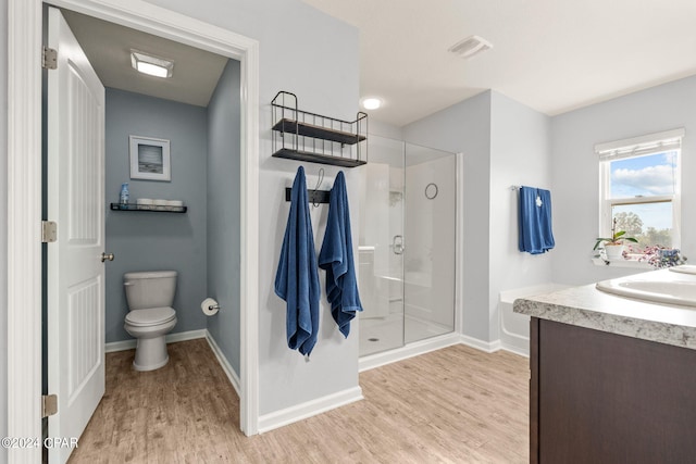 bathroom featuring wood-type flooring, a shower with shower door, vanity, and toilet