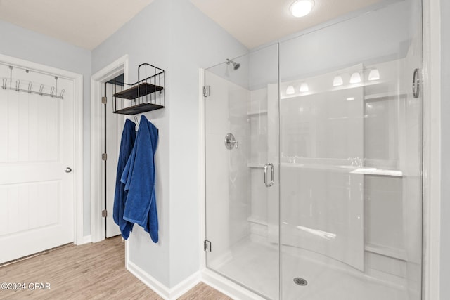 bathroom with hardwood / wood-style floors and a shower with shower door