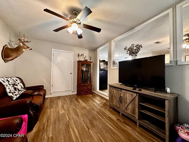 living room with a textured ceiling, hardwood / wood-style floors, and ceiling fan