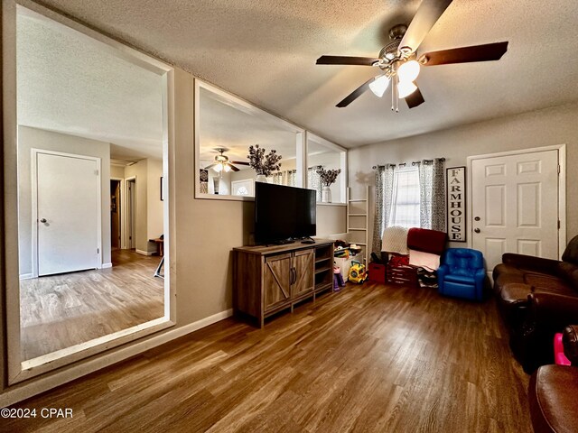 living room with a textured ceiling, ceiling fan, and hardwood / wood-style flooring