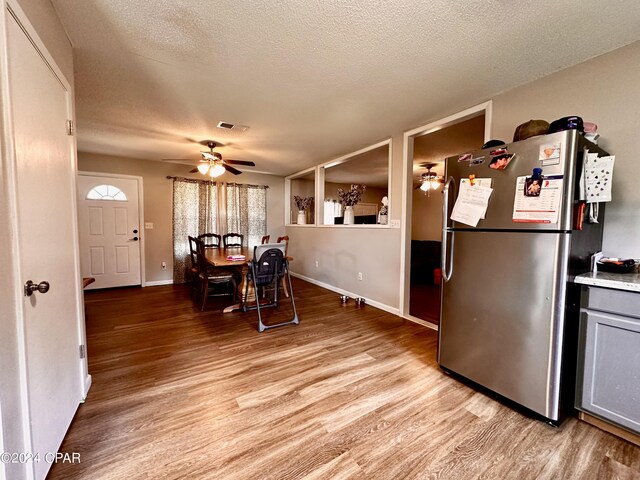 dining space with a textured ceiling, ceiling fan, and light hardwood / wood-style flooring