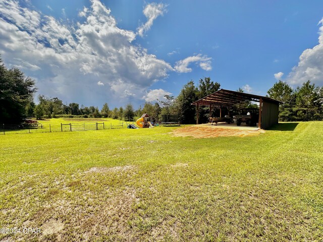 view of yard with a playground, a rural view, and a carport