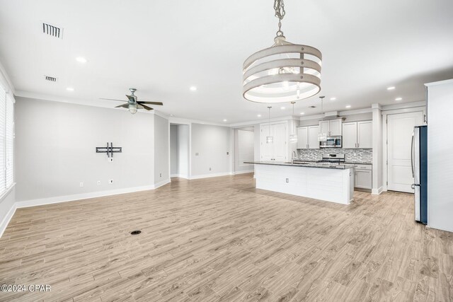 kitchen with a center island with sink, white cabinetry, appliances with stainless steel finishes, and pendant lighting