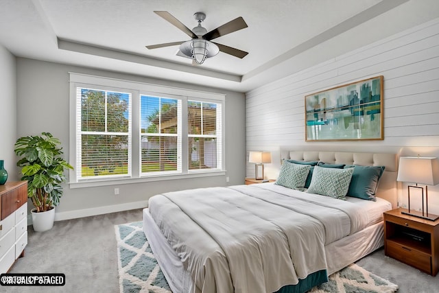 carpeted bedroom with a tray ceiling and ceiling fan