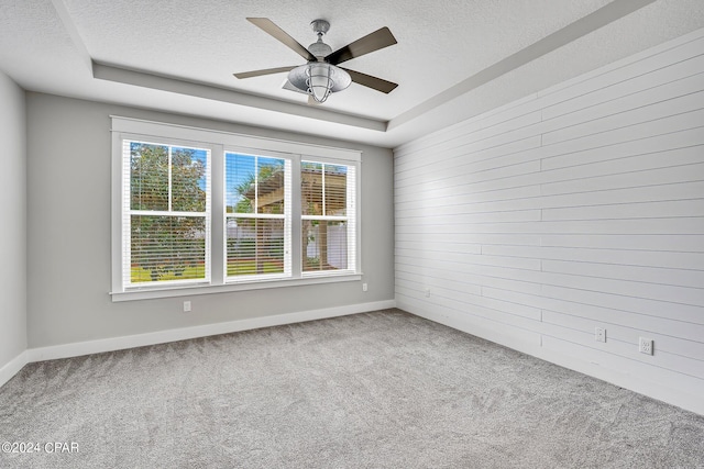 spare room featuring ceiling fan, a tray ceiling, carpet, and a textured ceiling