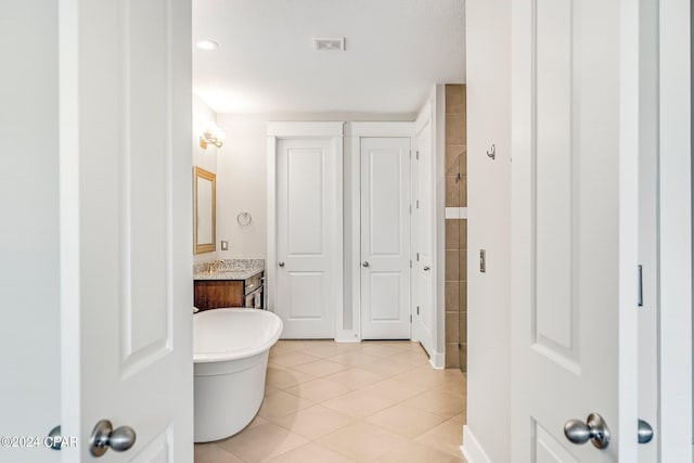 bathroom with tile patterned flooring, vanity, and a tub to relax in