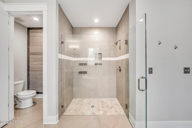 bathroom with tile patterned flooring, a shower with shower door, and toilet