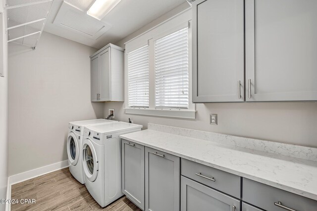 clothes washing area with cabinets, light hardwood / wood-style floors, and washing machine and dryer