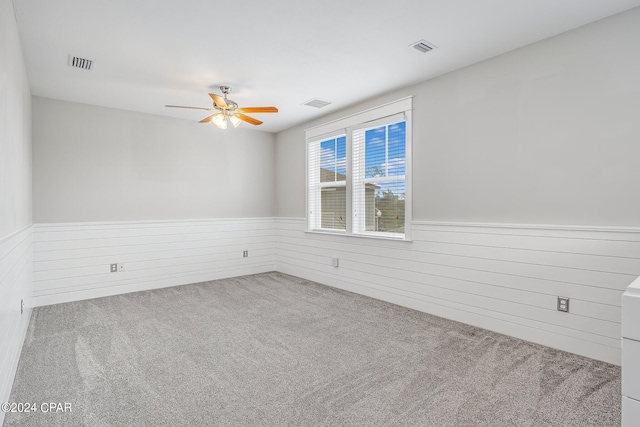 carpeted empty room featuring ceiling fan and wood walls