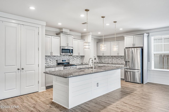 kitchen featuring pendant lighting, sink, a kitchen island with sink, light hardwood / wood-style floors, and stainless steel appliances