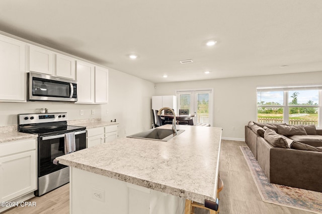 kitchen featuring a kitchen island with sink, light hardwood / wood-style flooring, stainless steel appliances, and white cabinets