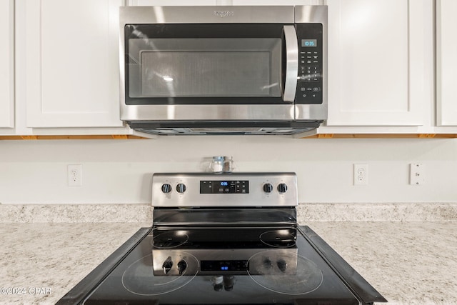 room details featuring light stone counters, appliances with stainless steel finishes, and white cabinetry