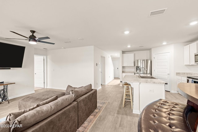 living room featuring ceiling fan, sink, and light hardwood / wood-style floors