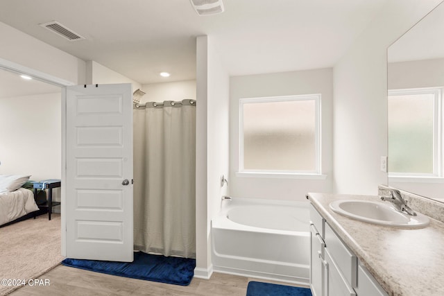 bathroom featuring independent shower and bath, vanity, hardwood / wood-style floors, and a wealth of natural light