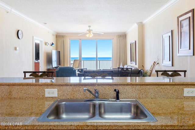 kitchen featuring a textured ceiling, ornamental molding, sink, and ceiling fan