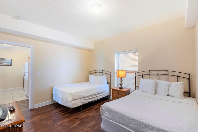 bedroom with a textured ceiling, dark hardwood / wood-style flooring, and white fridge