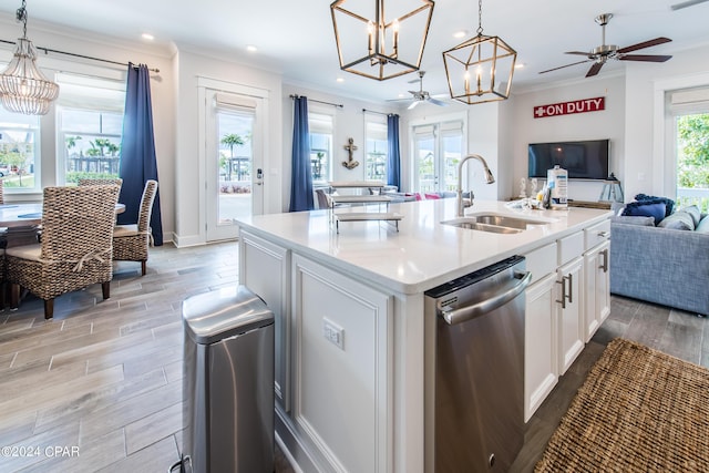 kitchen with ornamental molding, open floor plan, wood tiled floor, stainless steel dishwasher, and a sink