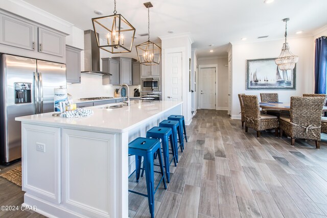 kitchen with a kitchen island with sink, wall chimney exhaust hood, sink, and stainless steel appliances