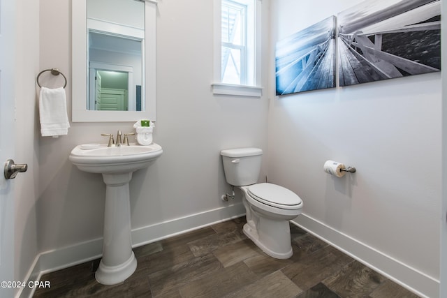 bathroom featuring toilet, baseboards, and wood finished floors