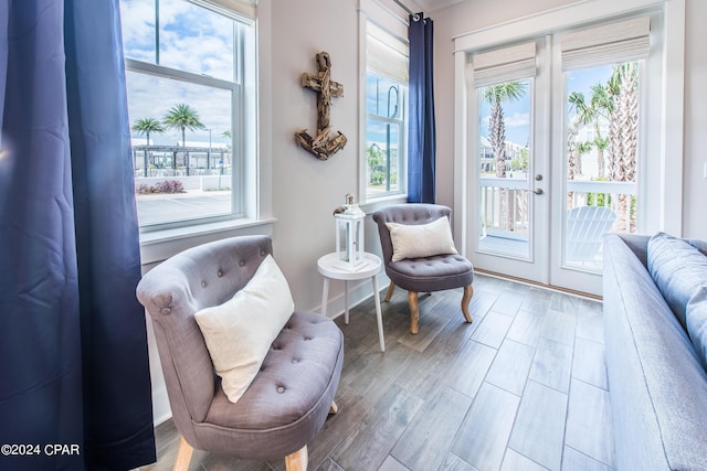 sitting room with baseboards, french doors, wood finished floors, and a healthy amount of sunlight