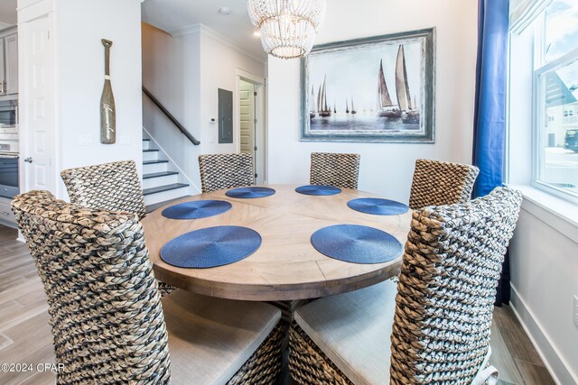 dining room featuring a chandelier, hardwood / wood-style floors, ornamental molding, and electric panel