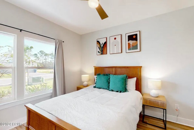 bedroom with multiple windows, light hardwood / wood-style floors, and ceiling fan