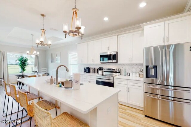 kitchen with appliances with stainless steel finishes, a center island with sink, and a healthy amount of sunlight