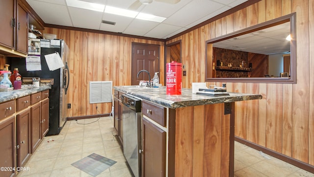 kitchen featuring an island with sink, wood walls, sink, and a paneled ceiling