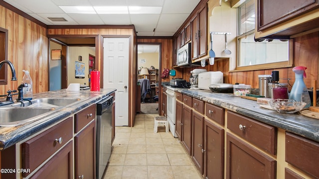 kitchen with wooden walls, appliances with stainless steel finishes, a paneled ceiling, and sink