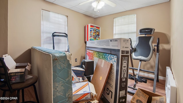 bedroom featuring ceiling fan, a drop ceiling, hardwood / wood-style floors, and radiator heating unit