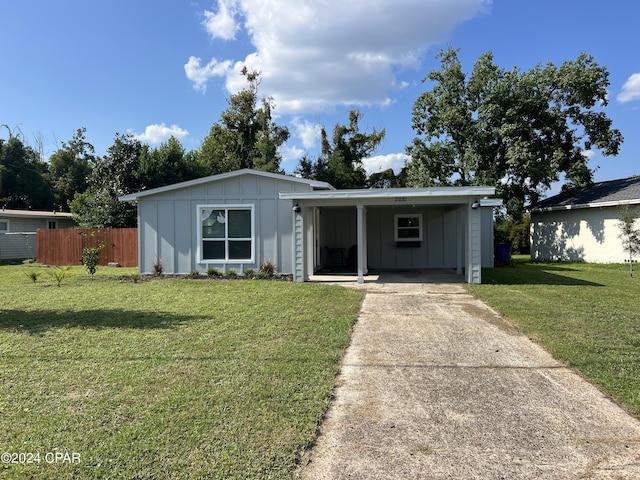 view of front facade with driveway, board and batten siding, an attached carport, a front yard, and fence