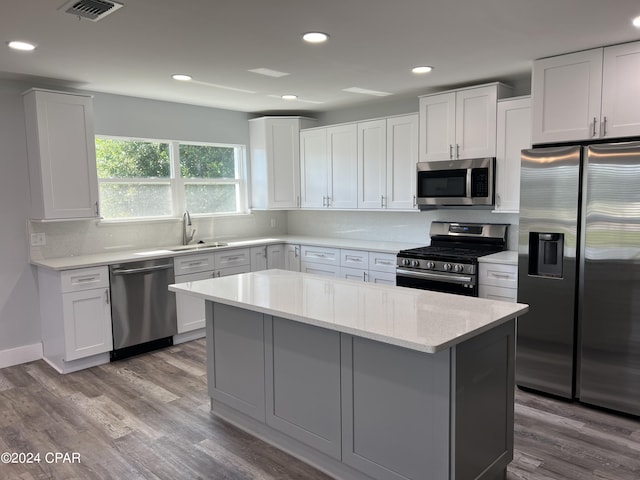 kitchen featuring white cabinets, light stone countertops, stainless steel appliances, light wood-type flooring, and sink