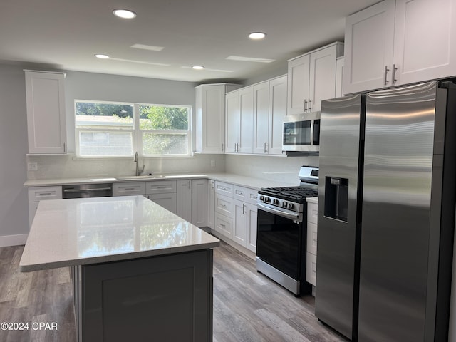 kitchen with light stone counters, a center island, white cabinetry, light hardwood / wood-style flooring, and appliances with stainless steel finishes