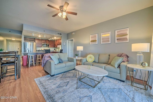 living room with ceiling fan, light wood-type flooring, and track lighting