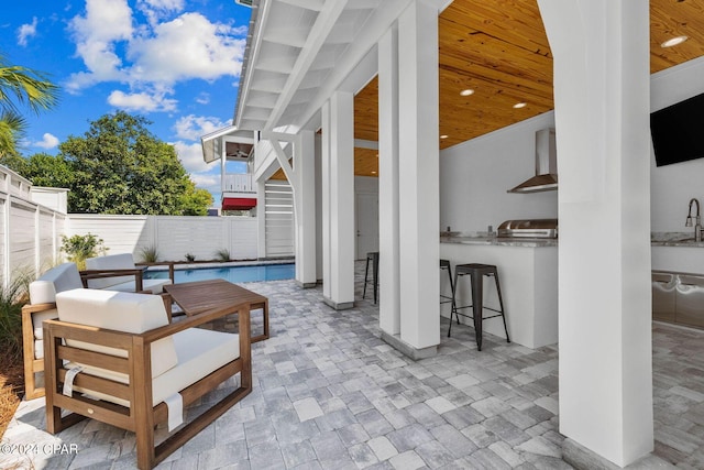 view of patio featuring area for grilling, a fenced in pool, and a wet bar