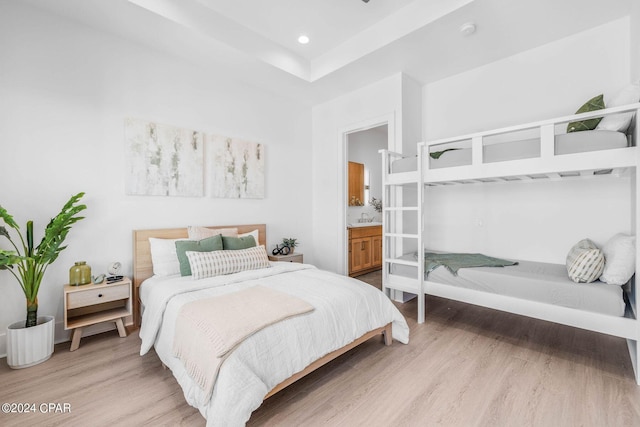 bedroom with ensuite bath, light hardwood / wood-style floors, and sink