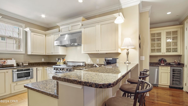 kitchen featuring beverage cooler, kitchen peninsula, a kitchen breakfast bar, stainless steel appliances, and extractor fan