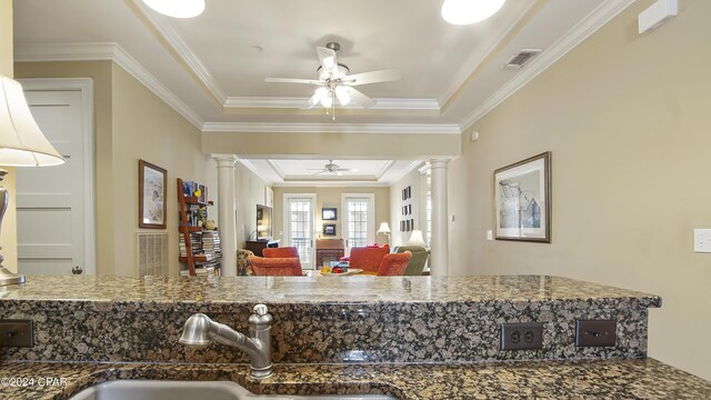 kitchen featuring ceiling fan, ornamental molding, a raised ceiling, and decorative columns