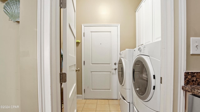 clothes washing area with independent washer and dryer, light tile patterned floors, and cabinets