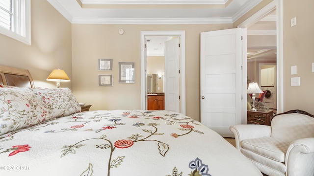 bedroom with ornamental molding, ensuite bath, and washer / dryer