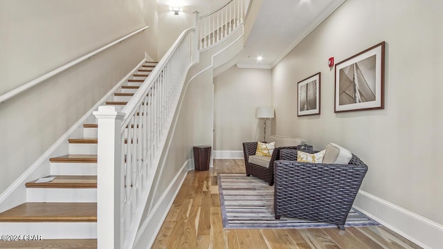 stairs with crown molding, baseboards, and wood finished floors
